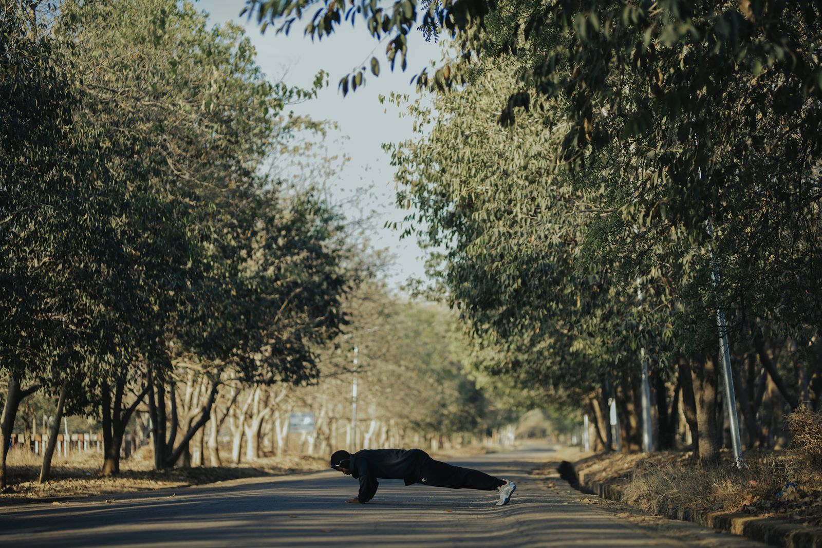Un hombre hace flexiones en un camino al aire libre.